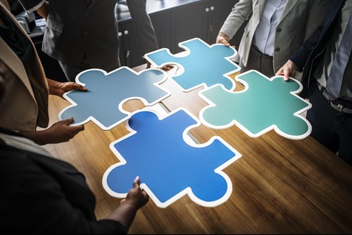 People standing around a table, slotting large jigsaw pieces together